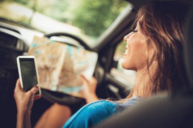 Yol haritaya bakıyordum ve smartphone kullanarak araba içinde genç gülümseyen kadın arkadan görünüş