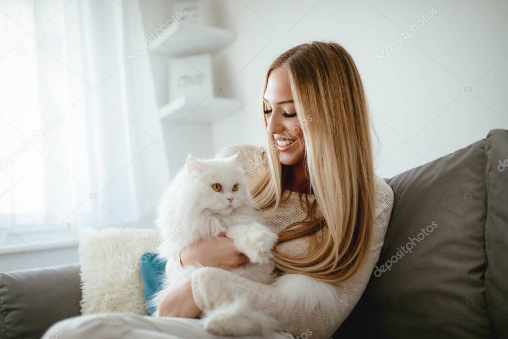 young woman relaxing at home and holding white Persian cat