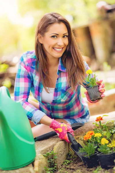 Young woman in gloves planting flowers in backyard