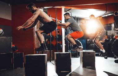 Spor salonunda zor egzersiz yaparak üç genç erkek arkadaş