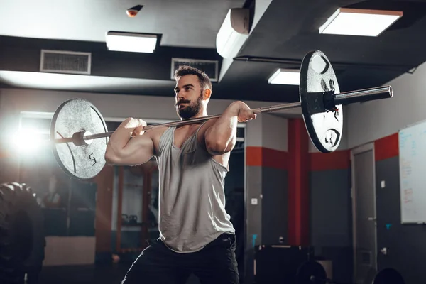 年轻的肌肉男子举重杠铃在健身房 — 图库照片