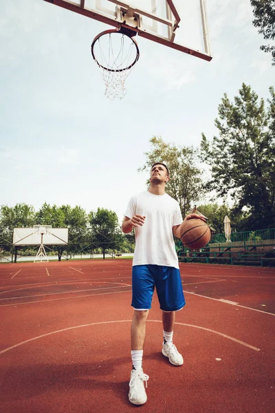 Young man training basketball on street court