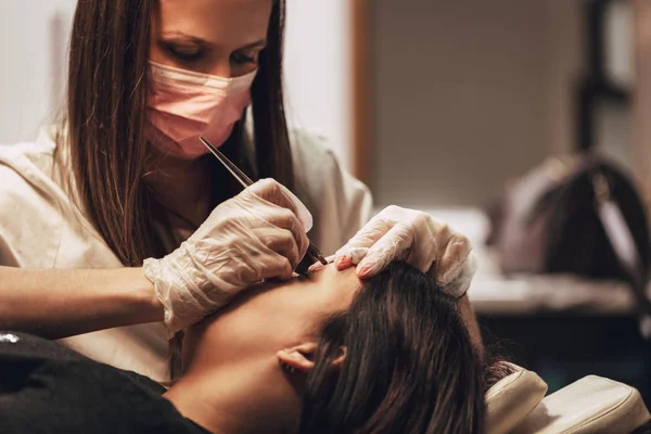 Beautician applying japanese method of drawing on eyebrows to model