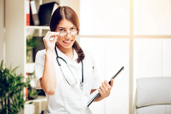 Junge Ärztin Steht Sprechzimmer Lächelt Und Blickt Die Kamera — Stockfoto