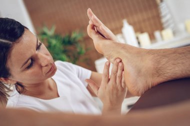 Genç kadın terapist spa-salonda genç erkek ayak masaj Görünümü Kapat