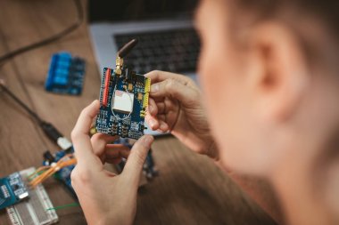Genç kadın teknisyeni havya tarafından elektronik donatımın tamiri üzerinde duruldu
