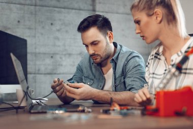 İki genç iş ortakları teknisyen elektronik donatımın tamiri üzerinde duruldu