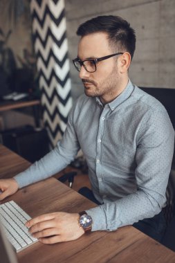 Ofiste bilgisayar üzerinde çalışan genç ciddi dalgın iş adamı