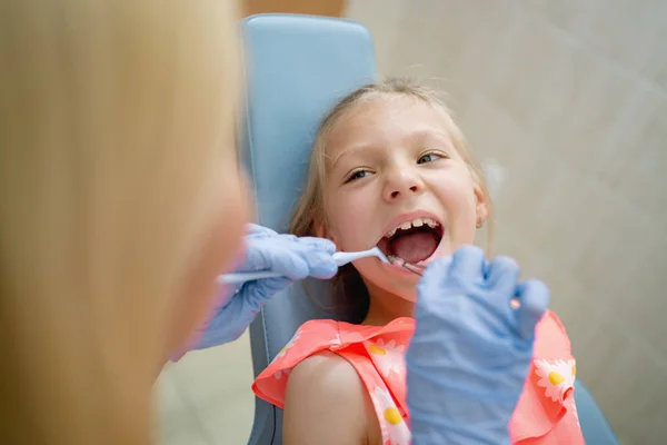 smiling girl at visit in dentist office and dentist checking teeth