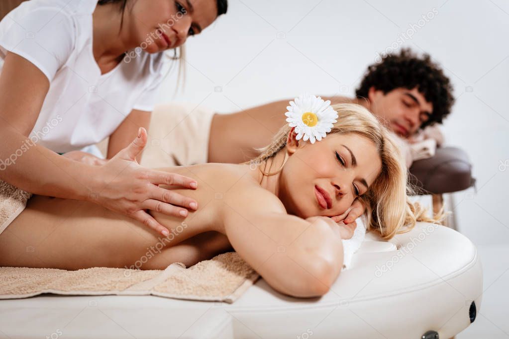 Young satisfied woman and man enjoying massage in beauty-salon