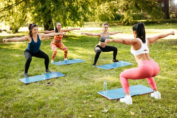 Jóvenes Deportistas Haciendo Sentadillas Ejercicio Parque Con Entrenador Fitness Femenino — Foto de Stock