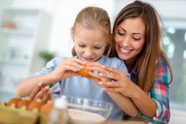 Anne ve küçük kızı yumurta çatlama iç mutfak yapımında hamur için un. Anne kızı nasıl çerezleri yapmak öğrenir..