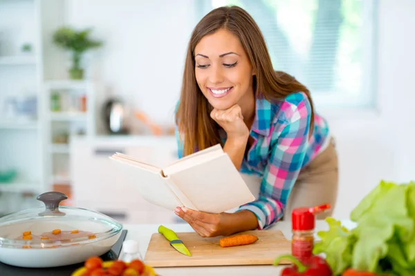 年轻妇女阅读食谱从食谱在家里 — 图库照片