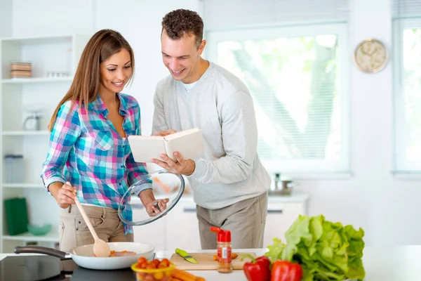年轻夫妇烹调健康膳食与食谱在家庭厨房里 — 图库照片