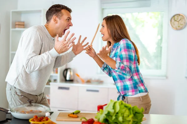 angry couple arguing, fighting and shouting at each other in domestic kitchen