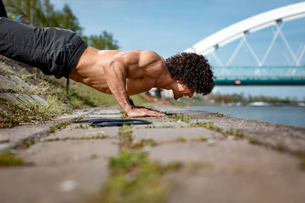 クロス川でトレーニング中に腕立て伏せをやって 裸の胴体を持つ筋肉若いスポーツ男 — ストック写真