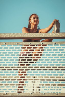 Genç bayan koşucu nehir köprüsünde esneme egzersizi yapıyor, sabah antrenmanına hazırlanıyor..