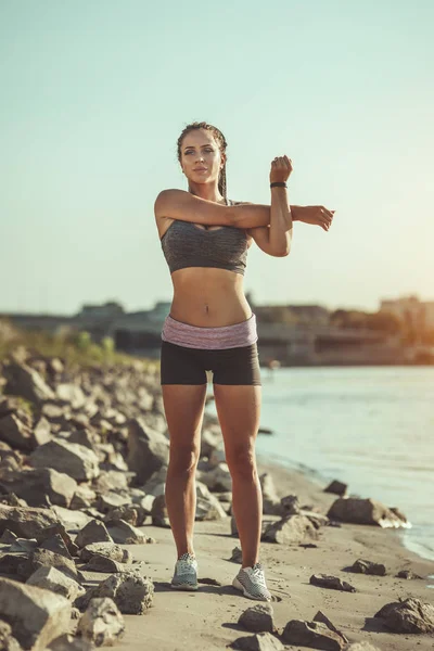 年轻的健身女性在河边做伸展运动 准备晨练 — 图库照片