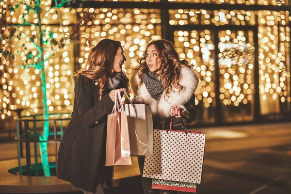 两个姐姐一边购物一边笑 手里拿着购物袋 享受着夜晚 — 图库照片