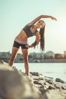 Genç fitness kadın nehir tarafından germe egzersiz yapıyor, sabah egzersiz için hazırlanıyor.