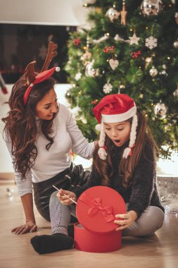 Şaşırmış küçük bir kız annesinden aldığı kırmızı kutuya bakar..