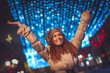 Neşeli genç bayan Noel zamanı şehir caddesinde eğleniyor..