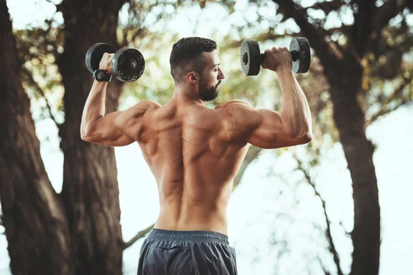 Apto Jovem Muscular Com Tronco Está Fazendo Exercícios Com Halteres — Fotografia de Stock