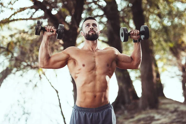 Apto Jovem Muscular Com Tronco Está Fazendo Exercícios Com Halteres — Fotografia de Stock