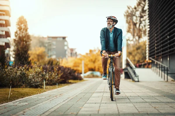 自転車で事務所に行くのはハンサムなカジュアルな中年のビジネスマンです オフィス街の前で自転車を運転している — ストック写真