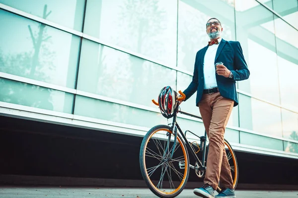彼の隣に自転車で成功した中年のビジネスマンは オフィス街の前を歩いてオフィスに行く — ストック写真