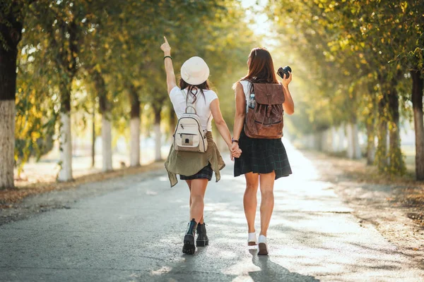 Dvě Krásné Mladé Ženy Batohy Zádech Kráčejí Podzimní Slunnou Ulicí — Stock fotografie