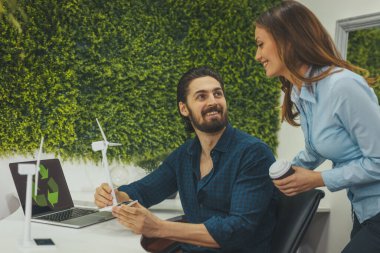 Zeki ilerici genç mühendisler ofisteki yel değirmeni projesinden bahsederken adam elinde küçük minyatür bir yel değirmeni türbini tutuyor..