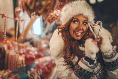 Neşeli genç bir kadın yeni yıl gecesinde şehir caddesindeki bir Noel pazarında eğleniyor..