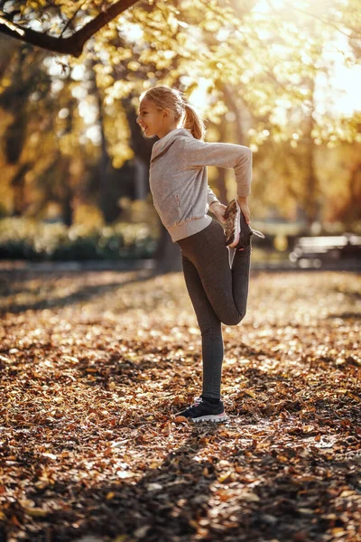 可爱的微笑的少女正在城市公园里做伸展运动 享受着阳光灿烂的秋日 — 图库照片