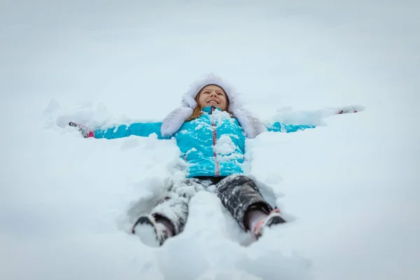 Χαριτωμένο Κοριτσάκι Χειμωνιάτικα Ρούχα Διασκεδάζει Ξαπλωμένο Καθαρό Λευκό Χιόνι — Φωτογραφία Αρχείου