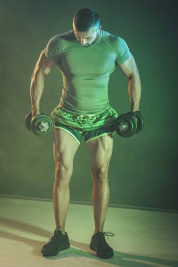 Yoğunlaşmış yakışıklı kaslı adam halterle aktif ve sıkı çalışıyor..