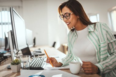 Genç ve başarılı bir bayan tasarımcı ofiste yeni bir proje üzerinde çalışıyor.. 