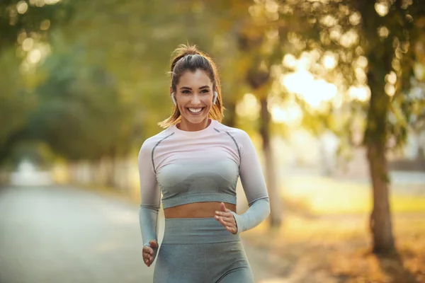 Mujer Feliz Usando Ropa Deportiva Con Auriculares Está Trotando Largo —  Fotos de Stock