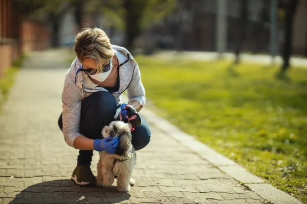 医療保護マスクの女性は 彼女の親愛なるかわいいですShih Tzu犬と一緒に街の通りのパスに沿って歩いていますインフルエンザウイルス感染症やコロナウイルスの流行中に — ストック写真