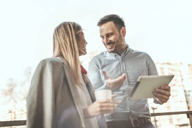 Genç ve başarılı meslektaşlar, ofisin önündeki balkondaki tartışma sırasında kahve molası veriyorlar..