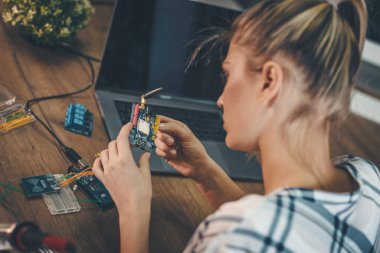 Genç bayan mühendis elektronik ekipmanların onarımına ve dizüstü bilgisayardaki bir şeyi kontrol etmeye odaklanmış durumda..