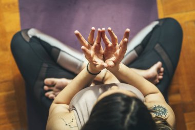 Genç bir kadının en iyi görüntüsü yoga Lotus Mudra 'sıdır - saflığın sembolü, bu mudra kalbi açar. Evde sabah güneşinde yerde meditasyon yapıyor..