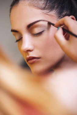 Güzel beyaz bir kadına makyaj yapan bir makyöz..