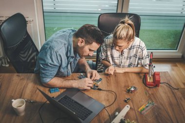 İki genç mühendis elektronik ekipmanların onarımına ve dizüstü bilgisayardaki bir şeyi kontrol etmeye odaklanmış durumda..