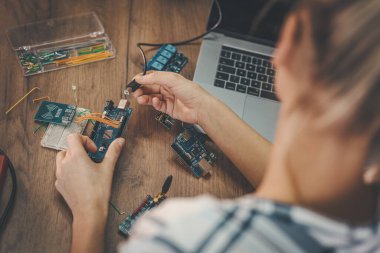 Genç bayan mühendis elektronik ekipmanların onarımına ve dizüstü bilgisayardaki bir şeyi kontrol etmeye odaklanmış durumda..