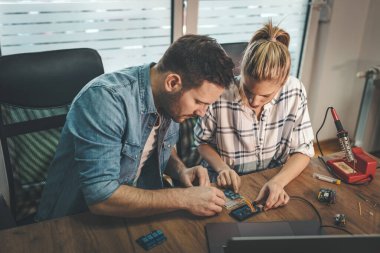 İki genç mühendis elektronik ekipmanların onarımına ve dizüstü bilgisayardaki bir şeyi kontrol etmeye odaklanmış durumda..