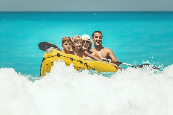 快乐的家庭正在享受乘坐橡皮艇的乐趣 暑假期间 海浪在热带海水中把它们泼洒 — 图库照片