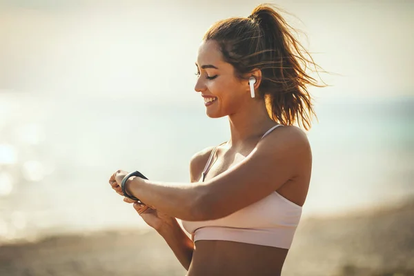 Femeie Tânără Frumoasă Uită Smartwatch Pregătește Facă Jogging Plaja Mării — Fotografie, imagine de stoc