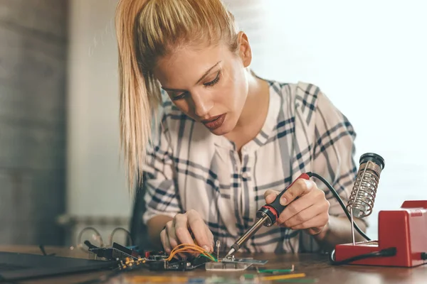 若い女性技術者は 鉄をはんだ付けして電子機器の修理に焦点を当てています — ストック写真