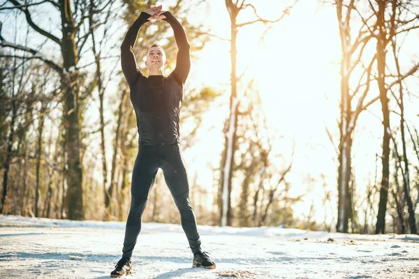 Aktywny Młodzieniec Wykonuje Ćwiczenia Rozciągające Leśnej Drodze Podczas Zimowego Treningu — Zdjęcie stockowe